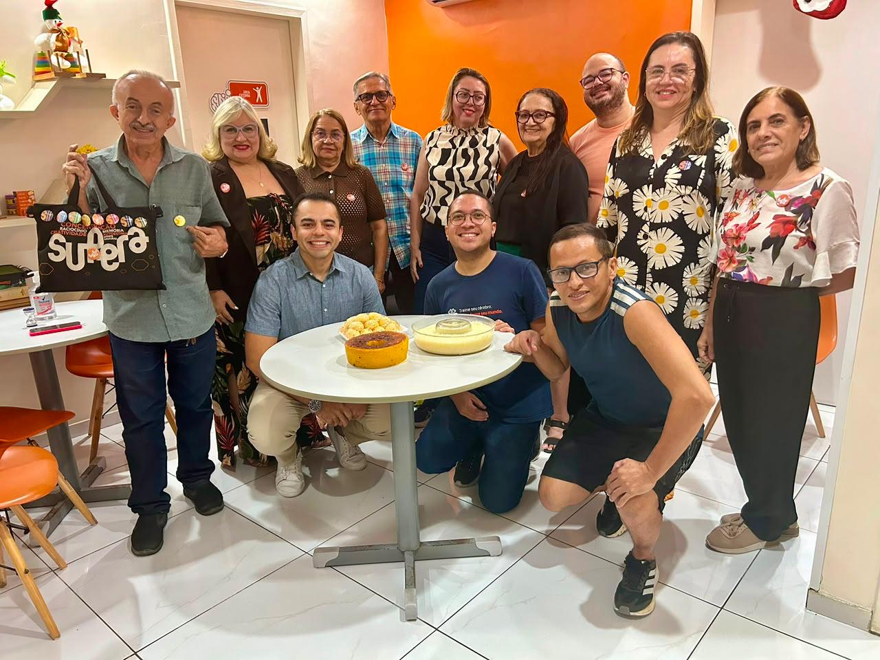 Alunos e equipe reunidos em volta da mesa com bolo, em confraternização